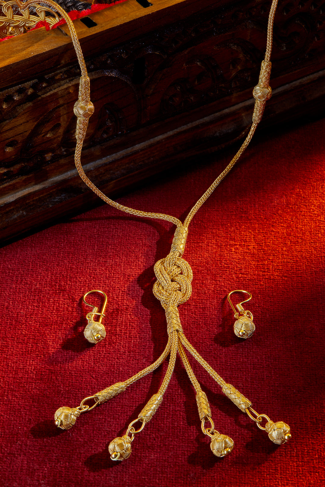 Gold necklace and earrings on a red fabric background